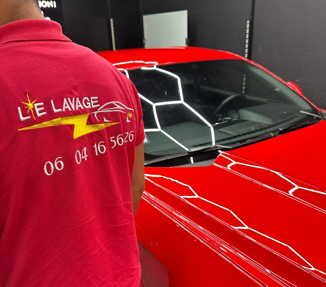 Dario Lalli de dos, polo Le Lavage 89, devant une voiture rouge sous une rampe d'éclairage hexagonale