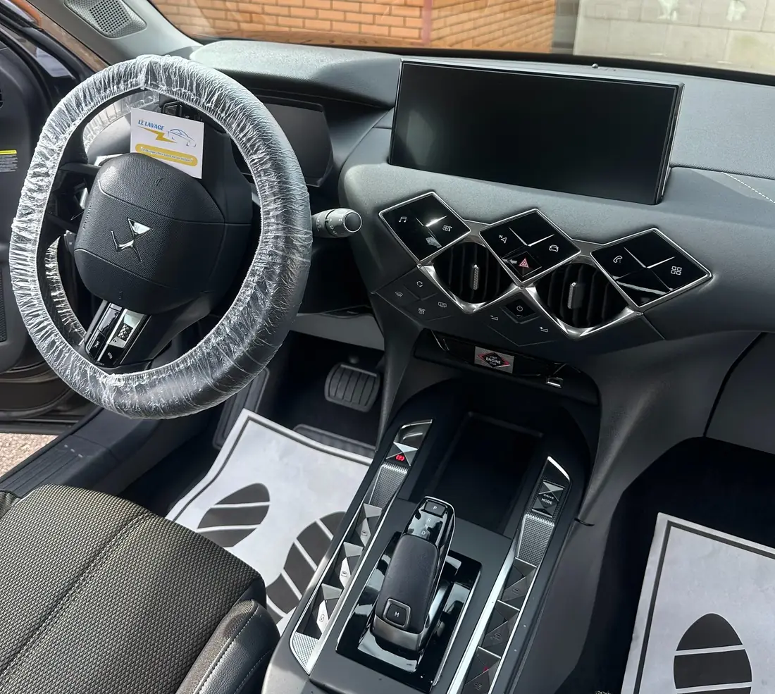 Intérieur d'une DS après nettoyage : housse de volant et tapis de protection au logo Le Lavage 89