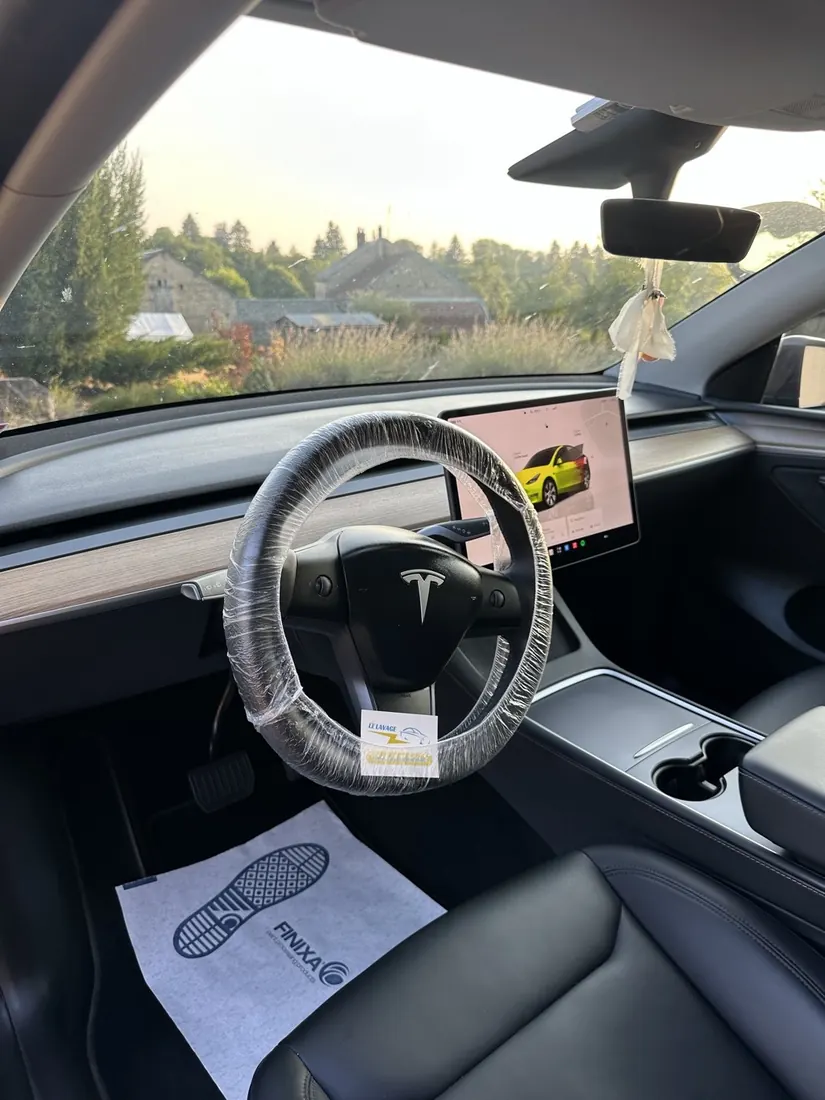 Intérieur d'une Tesla, housse de volant et tapis de protection en place