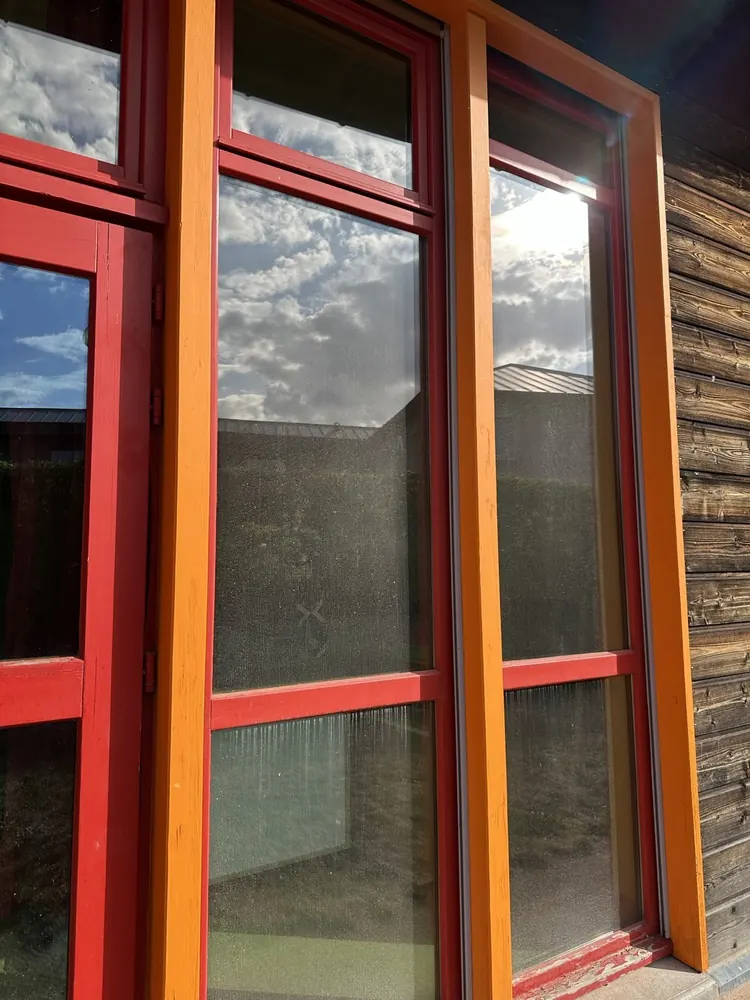 Vitrage propre reflétant le ciel, menuiseries rouges et orange